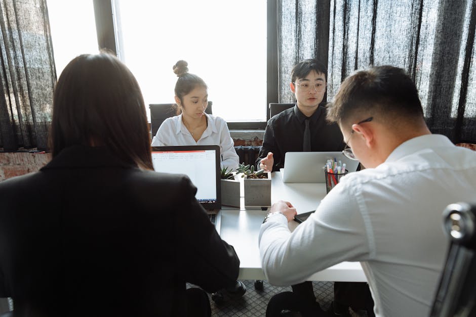 A team of professionals having a focused meeting in a modern office with laptops and a bright environment.