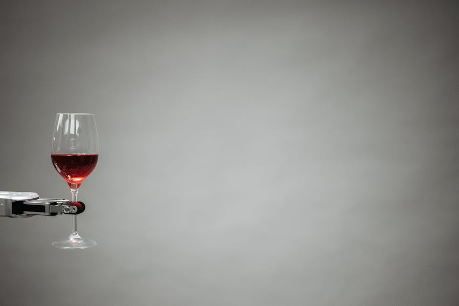 A robotic arm precisely holding a glass of red wine against a neutral background.